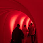 Originators Design, white stretch fabric shapes uses lighting to create a red rental tunnel.